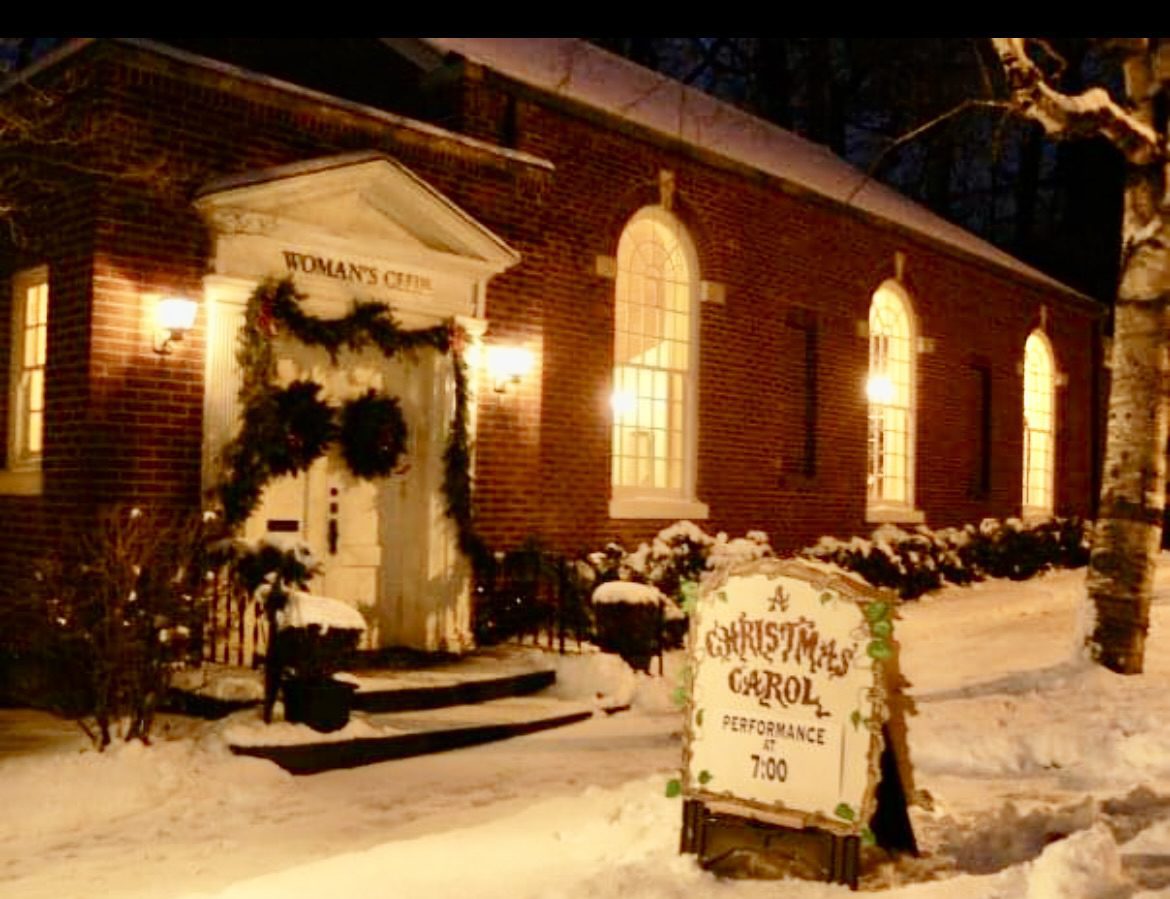 Snow-covered brick building with Christmas sign