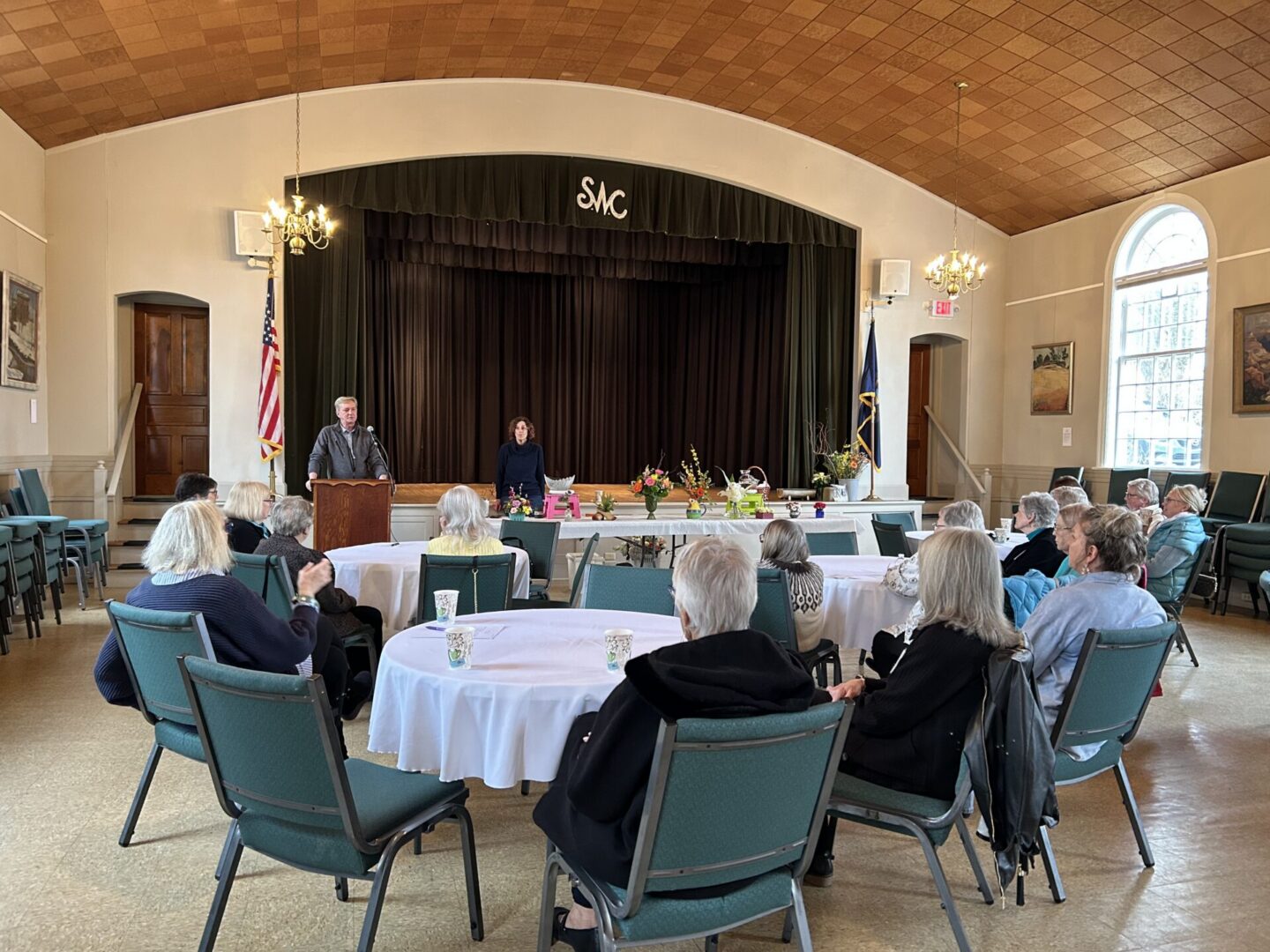 People seated at tables listening to speaker