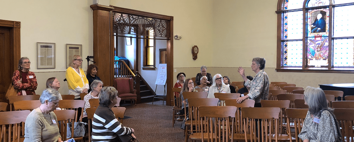 Woman addressing seated attendees in chapel