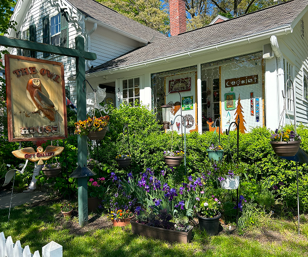White cottage with owl sign and flowers